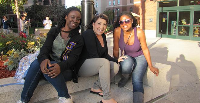 三个学生坐在校园大楼外的长凳上.